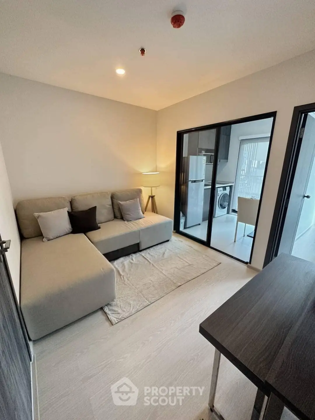 Modern living room with cozy sofa and open kitchen layout in stylish apartment.