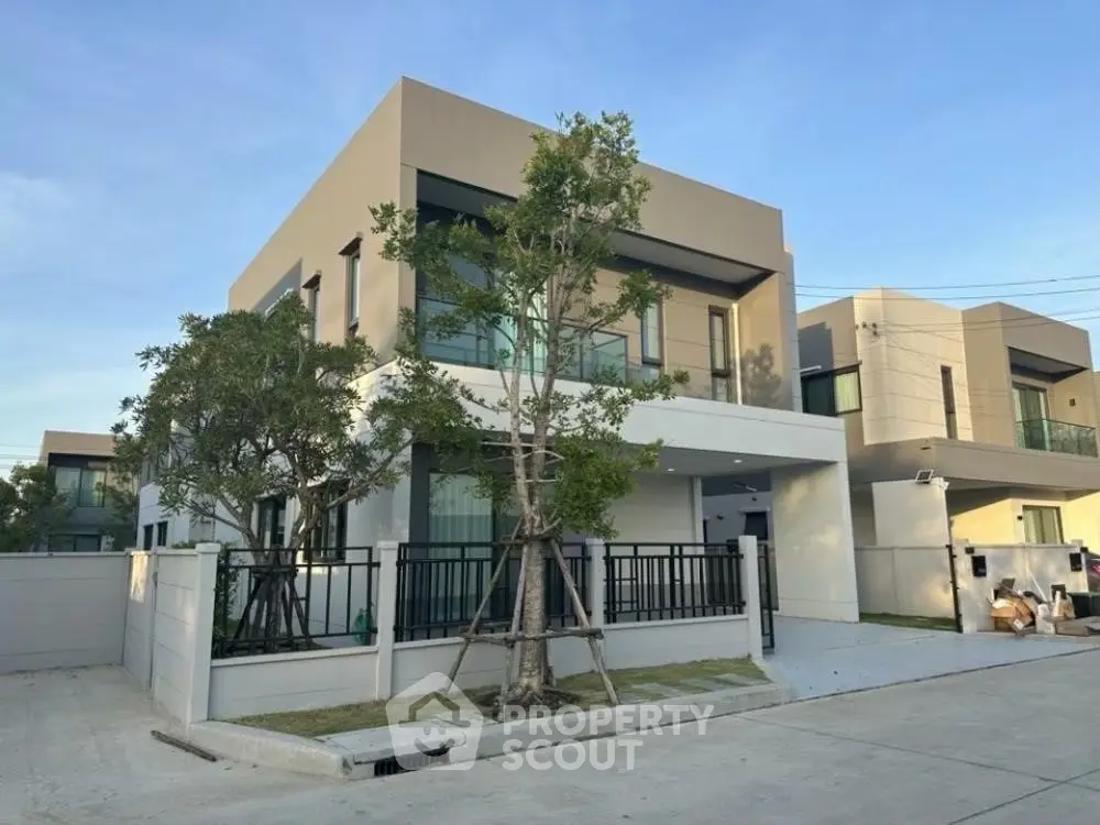Modern two-story house with sleek design and large windows, surrounded by greenery in a serene neighborhood.