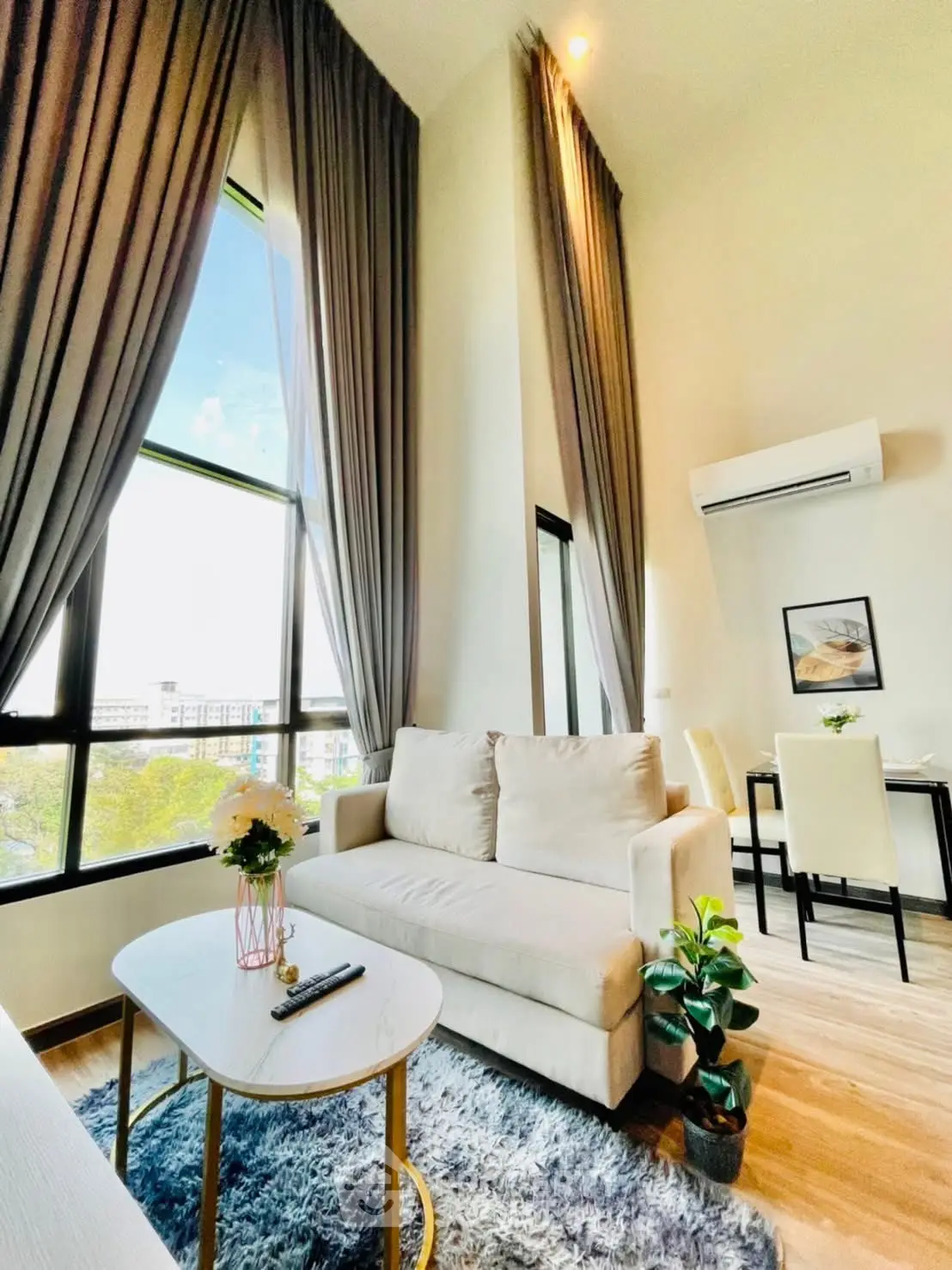 Bright and airy living room with high ceilings and large windows, featuring modern furniture and elegant decor.