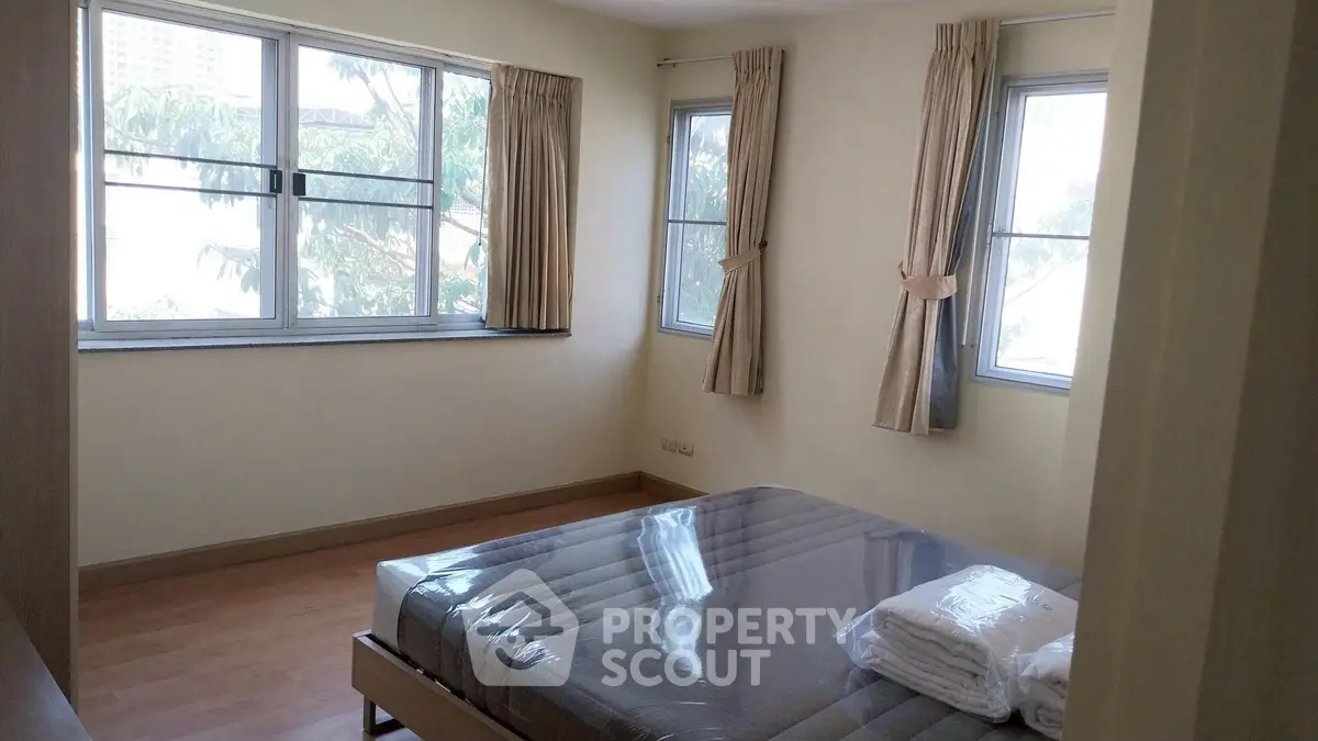 Spacious bedroom with large windows and natural light in modern apartment.