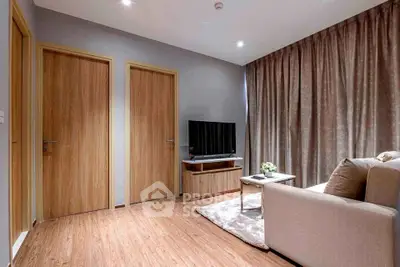 Modern living room with cozy sofa, flat-screen TV, and elegant wooden flooring.