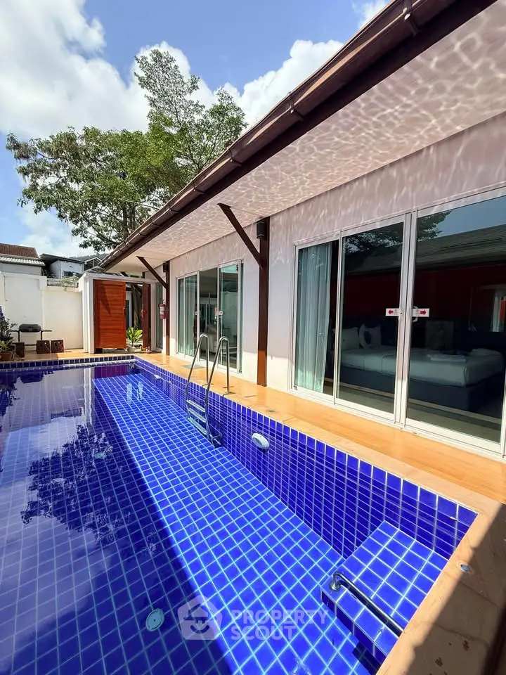 Luxurious villa with private blue-tiled pool and modern sliding glass doors, perfect for relaxation.