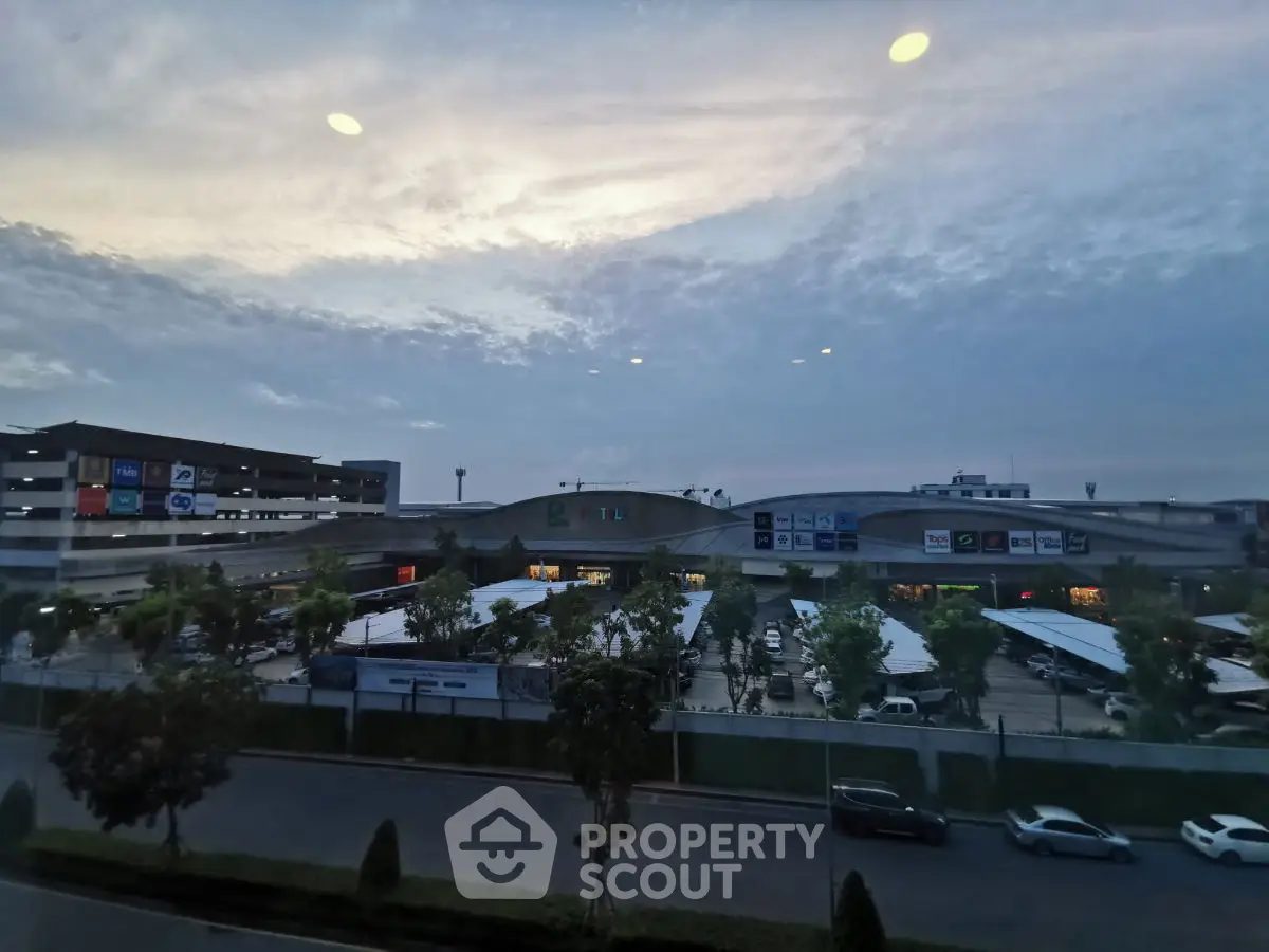 Scenic view of commercial building with parking and lush greenery at dusk
