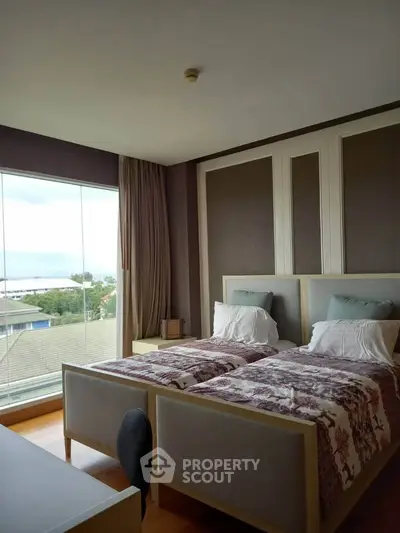 Spacious bedroom with twin beds and large window offering scenic views
