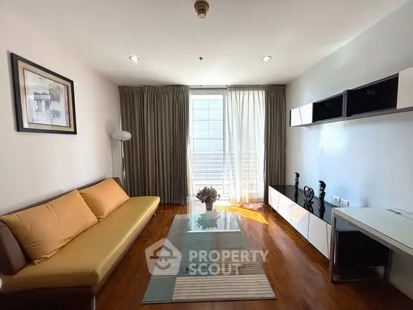 Modern living room with wooden flooring, stylish sofa, and natural light from large window.