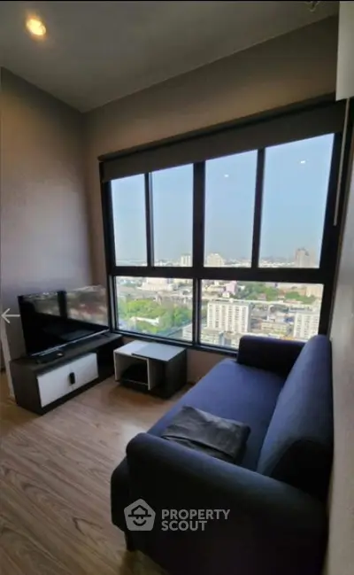 Cozy living room with stunning city view from large windows, featuring modern furniture and sleek design.