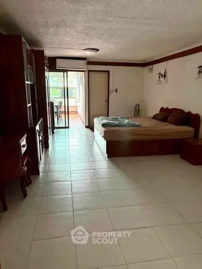 Spacious bedroom with balcony access in a cozy apartment, featuring elegant wooden furniture and ample natural light.