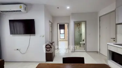 Modern apartment interior with wall-mounted TV, air conditioning, and open kitchen layout.