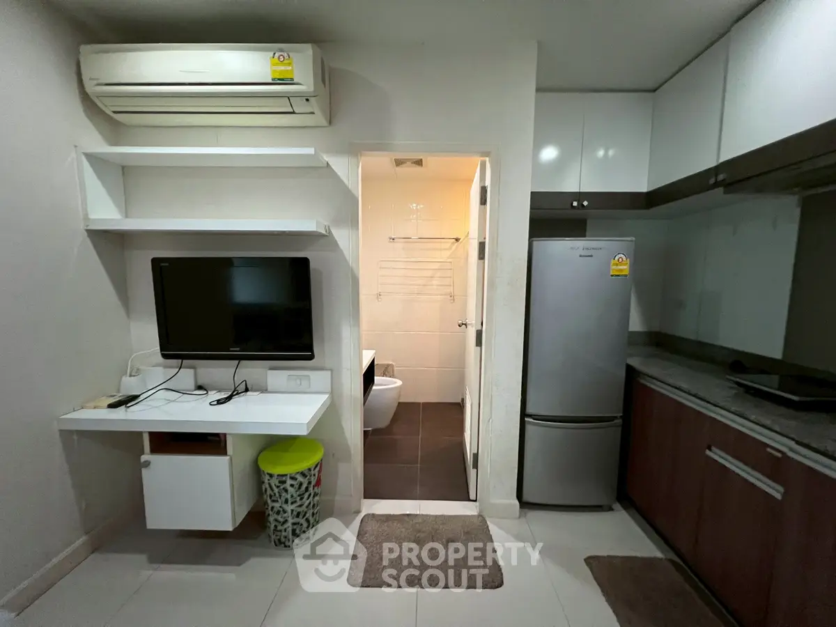 Modern apartment interior with kitchen and living area featuring air conditioning and sleek appliances.