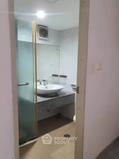 Compact bathroom with modern sink and glass shower enclosure