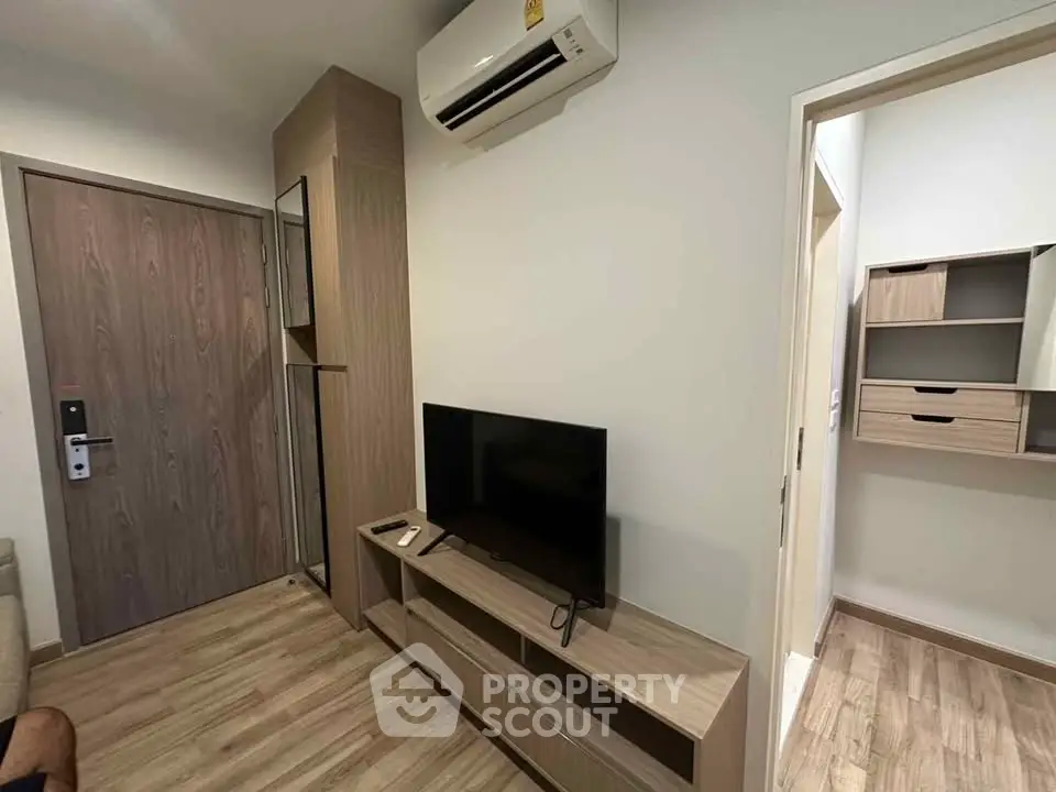 Modern living room with wooden flooring, TV unit, and air conditioning in a cozy apartment.