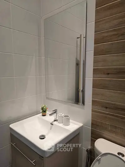 Modern bathroom with sleek sink and mirror, featuring stylish wood paneling.