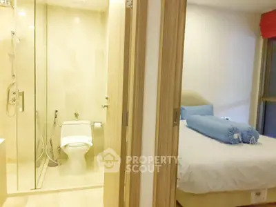 Modern bedroom with ensuite bathroom featuring glass shower and cozy bed setup.