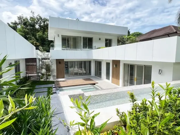 Modern luxury home with pool and lush garden, showcasing sleek architectural design.