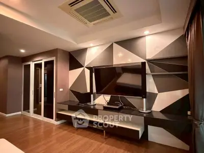 Modern living room with geometric wall design and sleek entertainment center.