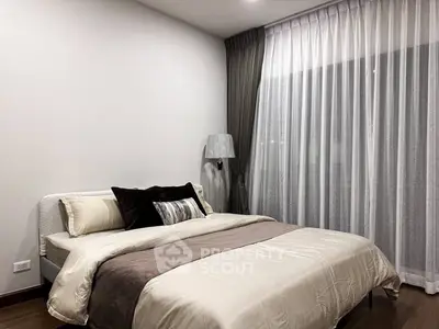 Elegant bedroom with modern decor and large window draped with sheer curtains, creating a cozy and inviting atmosphere.