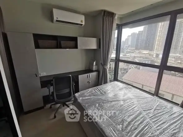 Modern bedroom with city view, featuring a desk and air conditioning, ideal for urban living.