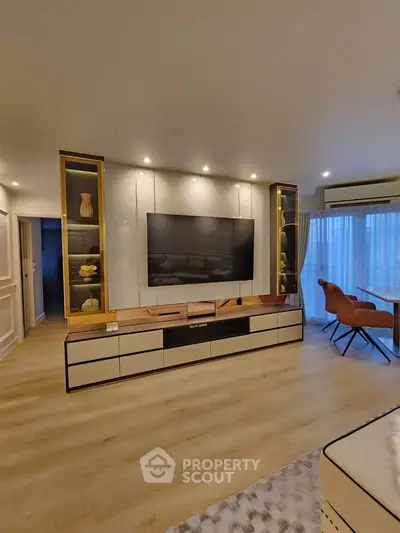 Modern living room with stylish TV unit and elegant decor, featuring cozy seating and natural light.