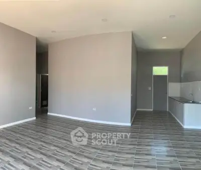 Spacious open-plan living area with modern tiled flooring and sleek kitchen design.