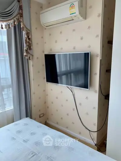 Cozy bedroom with wall-mounted TV and air conditioning, featuring elegant curtains and floral wallpaper.
