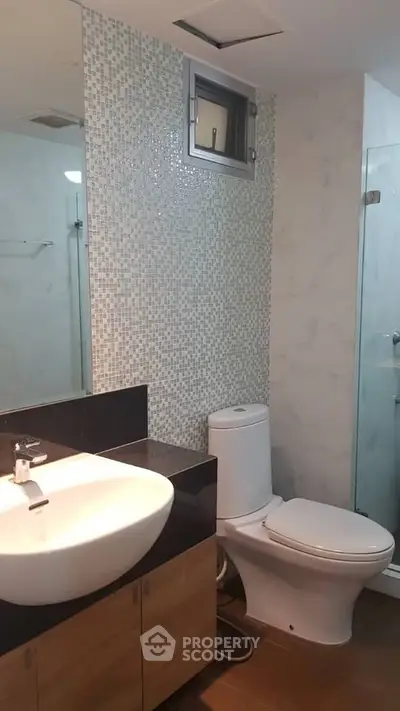 Modern bathroom with sleek fixtures and stylish mosaic tile accent wall.