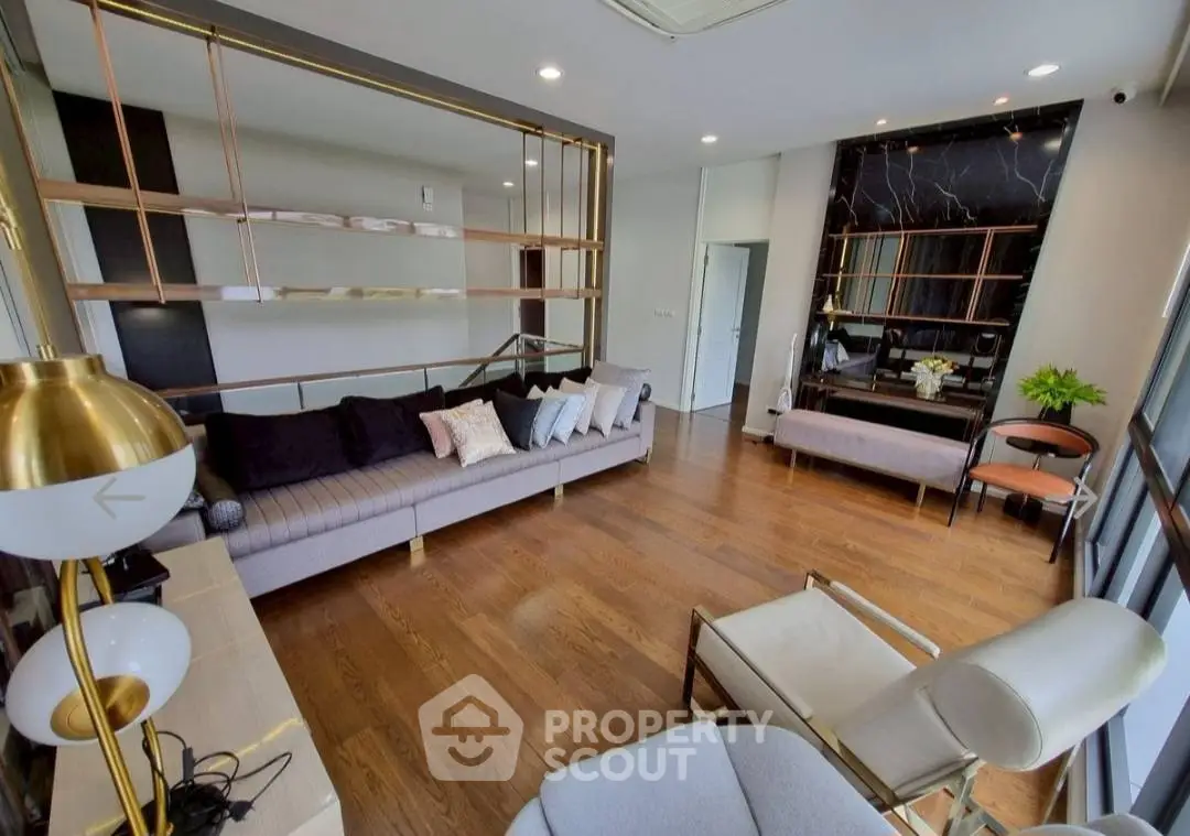 Modern living room with stylish decor and wooden flooring, featuring a cozy seating area and elegant lighting.