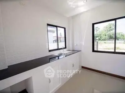 Modern kitchen with sleek black countertop and large windows offering natural light.