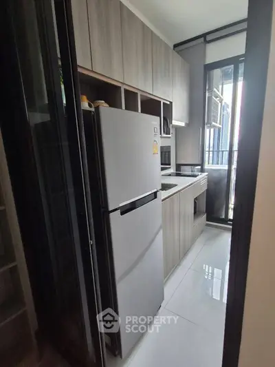 Modern kitchen with sleek cabinetry and large refrigerator in a compact layout.