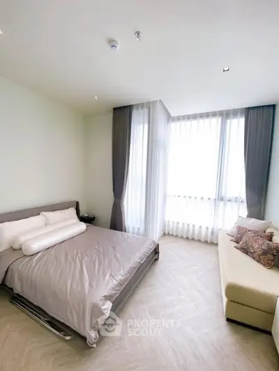 Spacious bedroom with modern decor and large windows for natural light