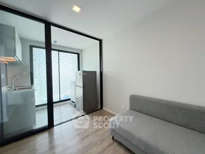 Modern apartment with sleek kitchen and cozy living area featuring a stylish sofa.