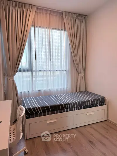 Cozy bedroom with single bed, modern decor, and large window with city view.