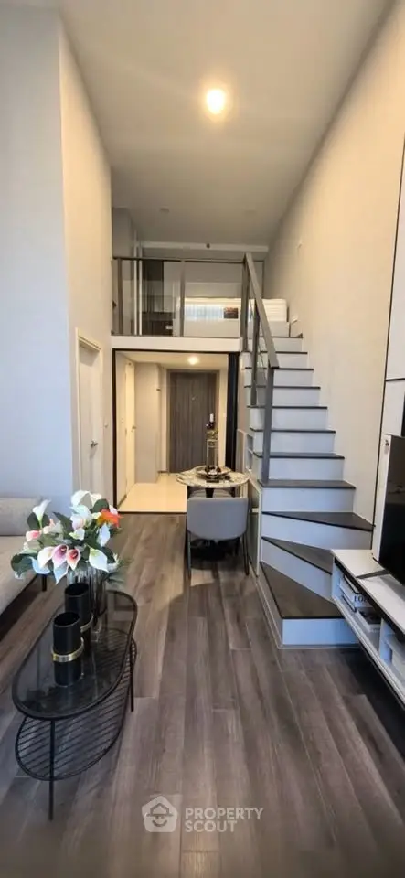 Modern loft-style living room with high ceilings and elegant staircase