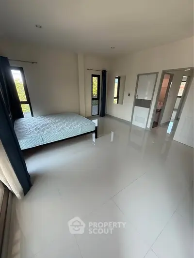 Spacious bedroom with large windows and minimalist design, offering abundant natural light and serene ambiance.