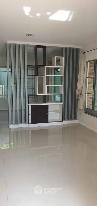 Modern living room with sleek shelving and large windows for natural light.