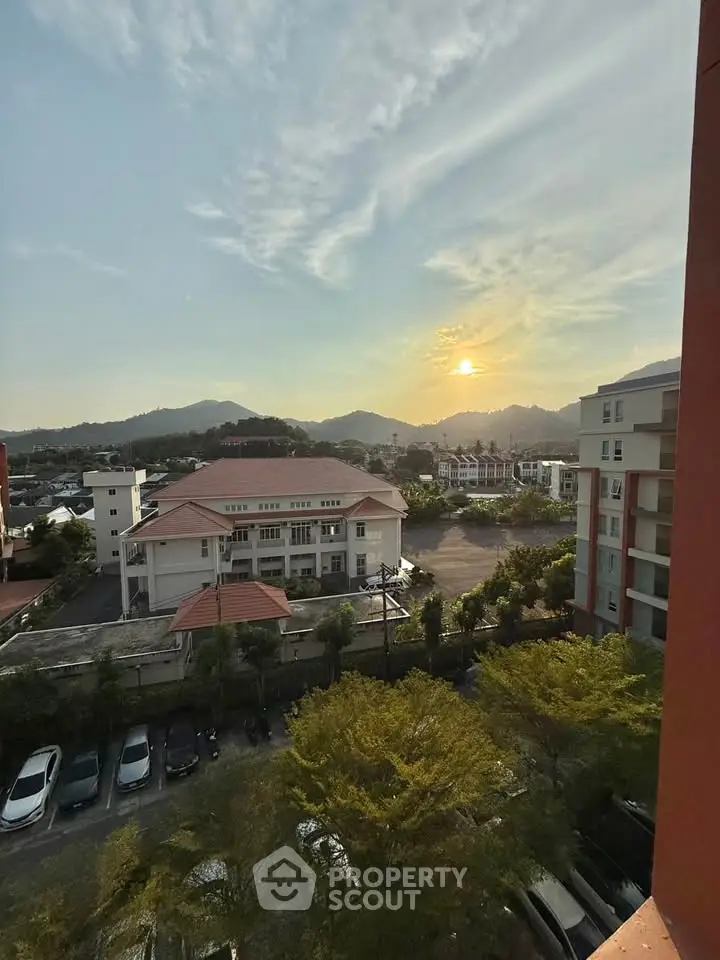 Stunning sunset view from high-rise apartment overlooking cityscape and mountains.