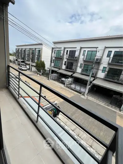 Modern balcony view overlooking contemporary townhouses and street.
