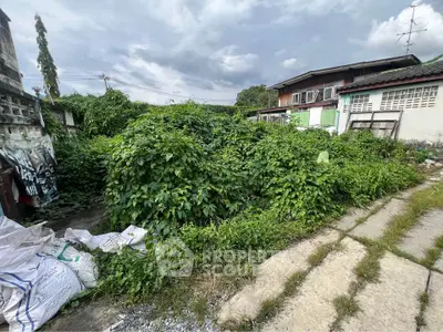 Vacant land with overgrown vegetation in a residential area, ideal for development opportunities.