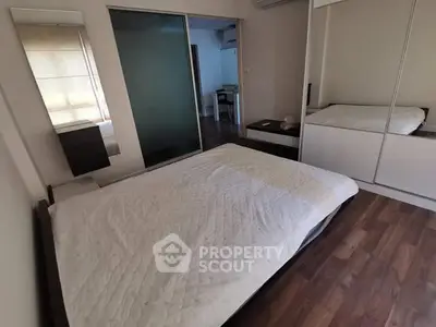 Spacious bedroom with wooden flooring and mirrored wardrobe