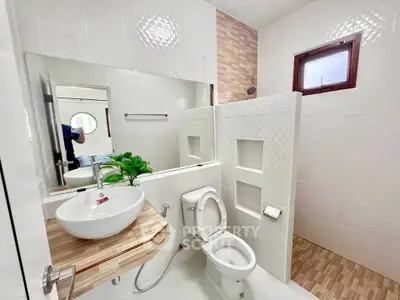 Modern bathroom with stylish sink and toilet, featuring elegant tile design and natural light.