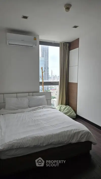 Modern bedroom with city view, featuring a cozy bed and air conditioning, perfect for urban living.