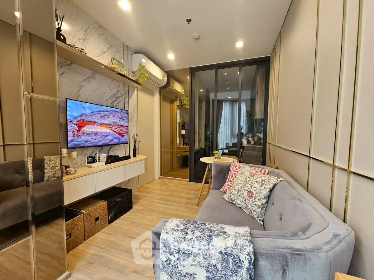 Modern living room with stylish decor and cozy seating area, featuring a wall-mounted TV and elegant shelving.