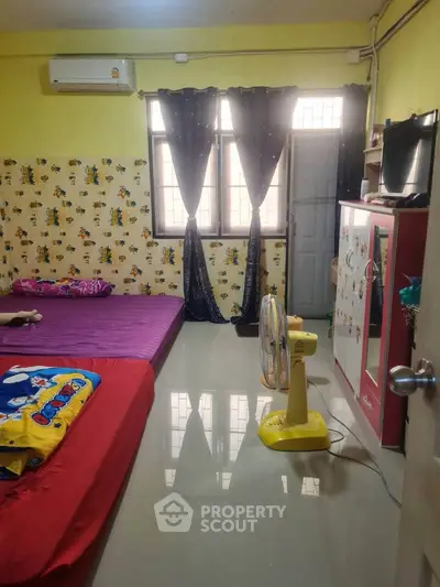 Cozy bedroom with colorful decor and natural light, featuring a fan and air conditioning for comfort.