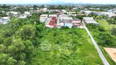 Aerial view of lush green land and residential area, ideal for development opportunities.