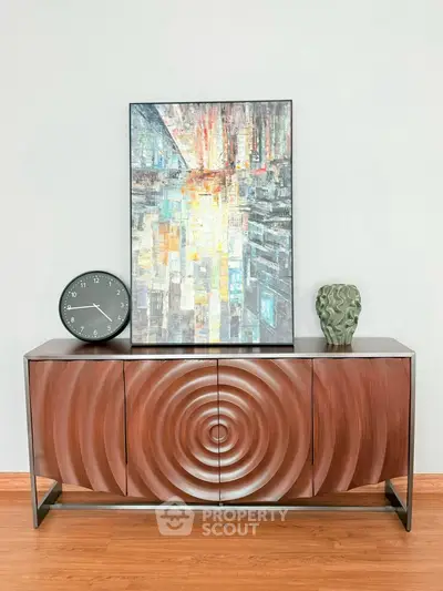 Stylish modern sideboard with artistic decor and clock in elegant living room.