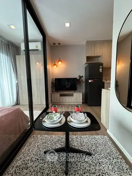 Modern open-plan living room with stylish decor and kitchen area in a cozy apartment.