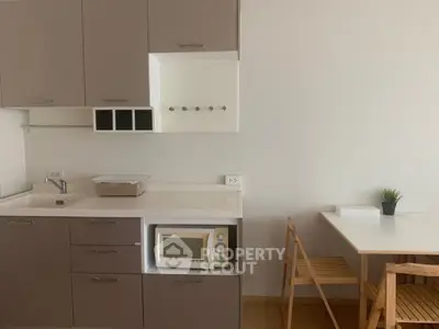 Modern compact kitchen with microwave and dining area in cozy apartment.