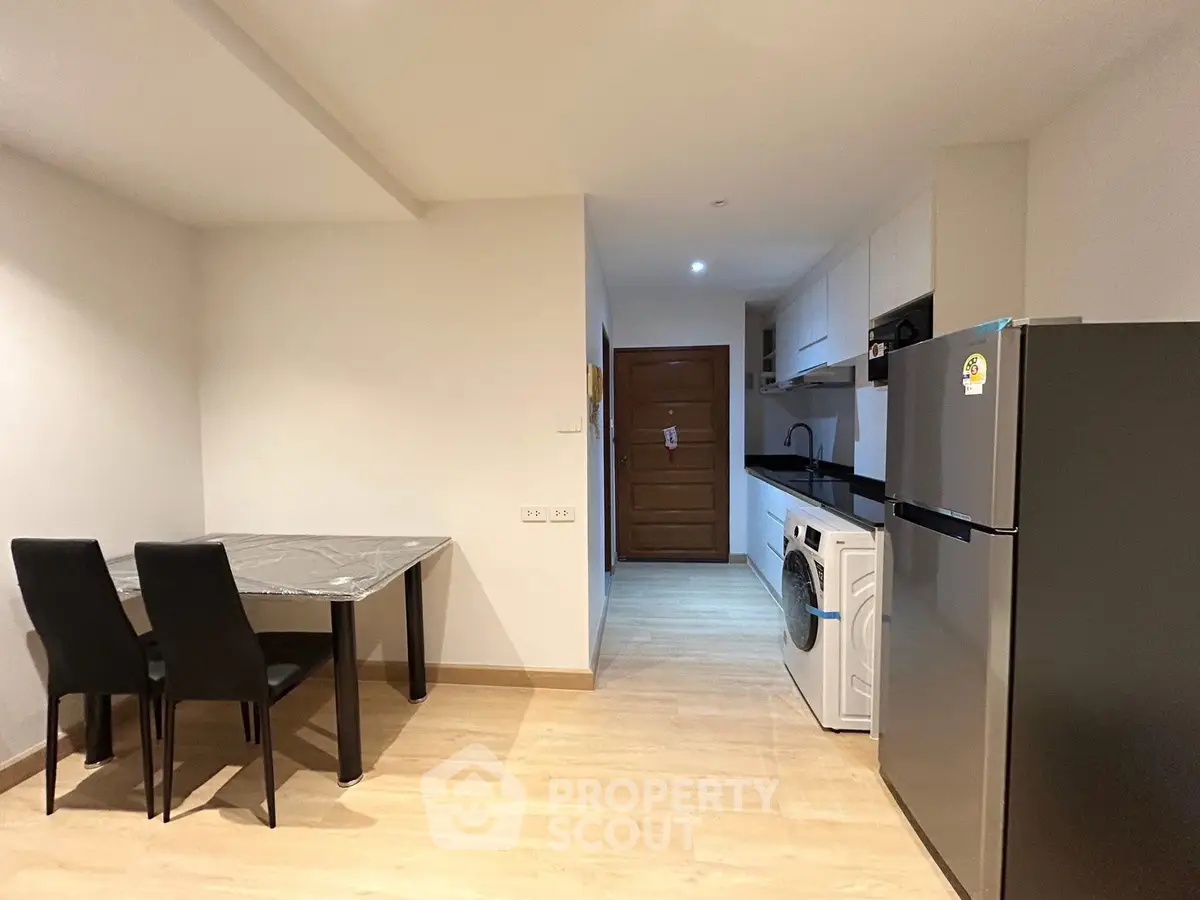 Modern kitchen with dining area, washing machine, and fridge in a sleek apartment.