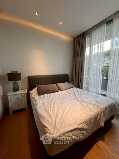 Cozy bedroom with large window and elegant decor, perfect for relaxation.