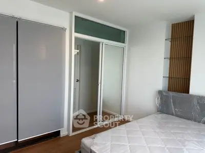 Modern bedroom with sleek design and large mirrored closet doors, featuring a partially furnished setup.