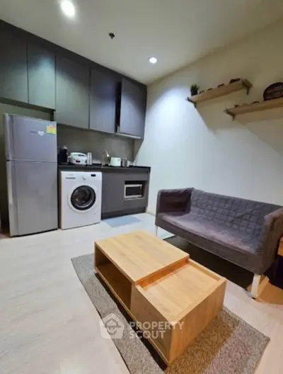 Modern compact kitchen with washing machine and cozy living area in stylish apartment.